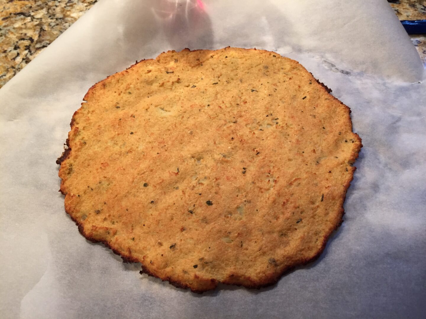 Baked cauliflower crust on parchment paper.