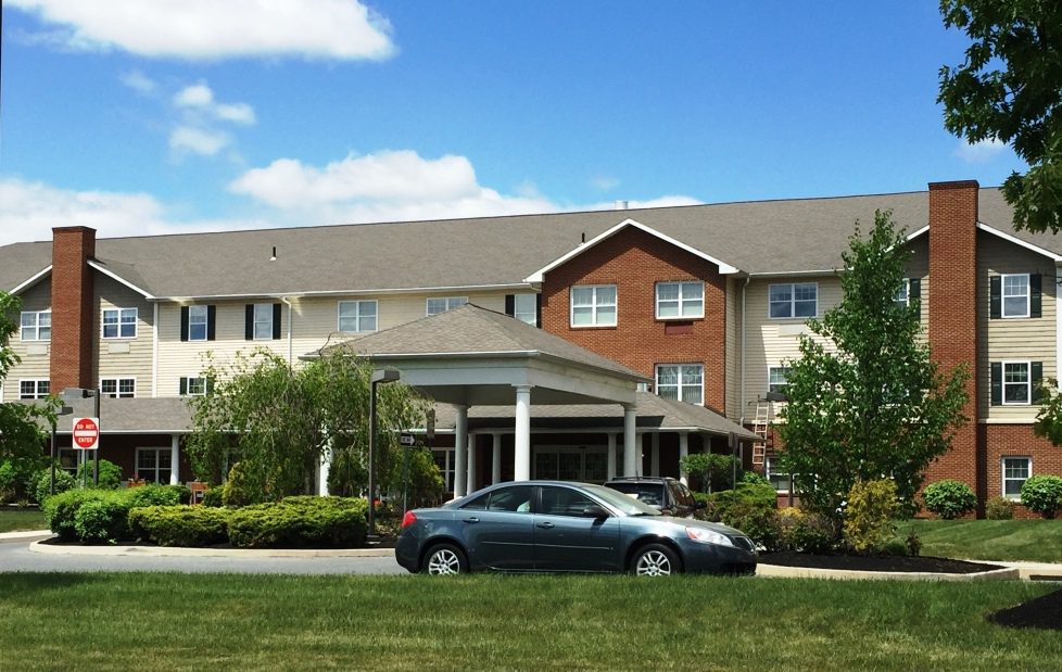 Three-story building with car in front.