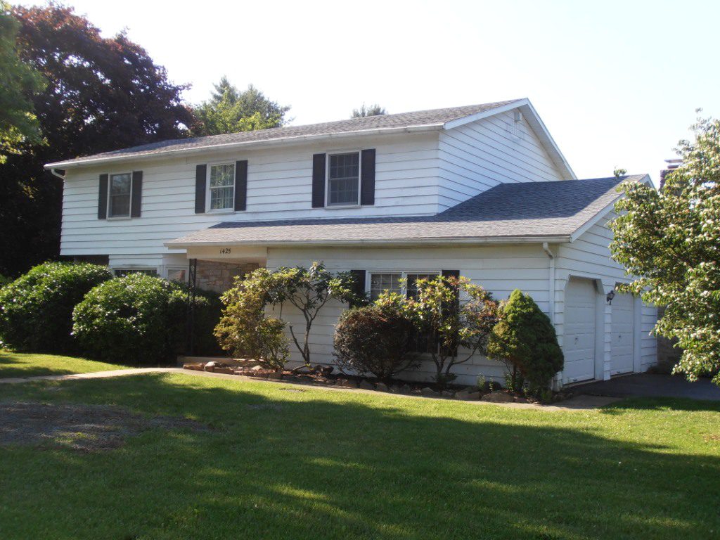Two-story white house with lush greenery.