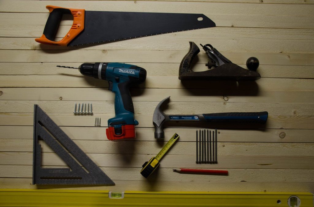 Assorted construction tools on wooden surface.