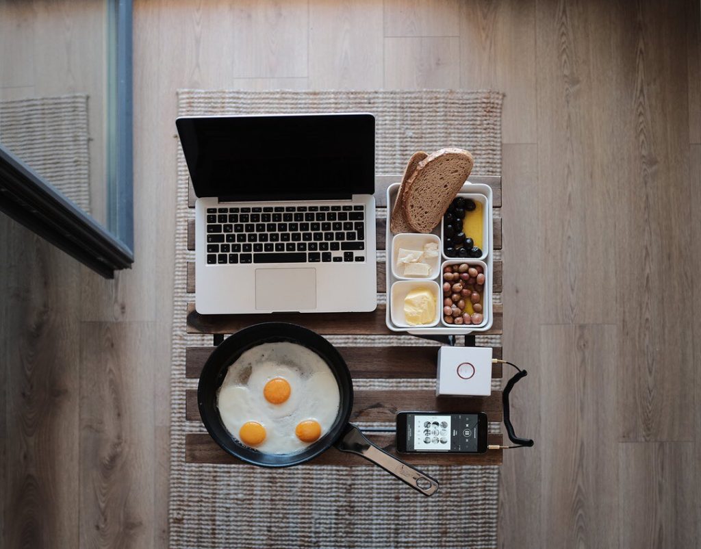 Breakfast setup with laptop and frying pan.